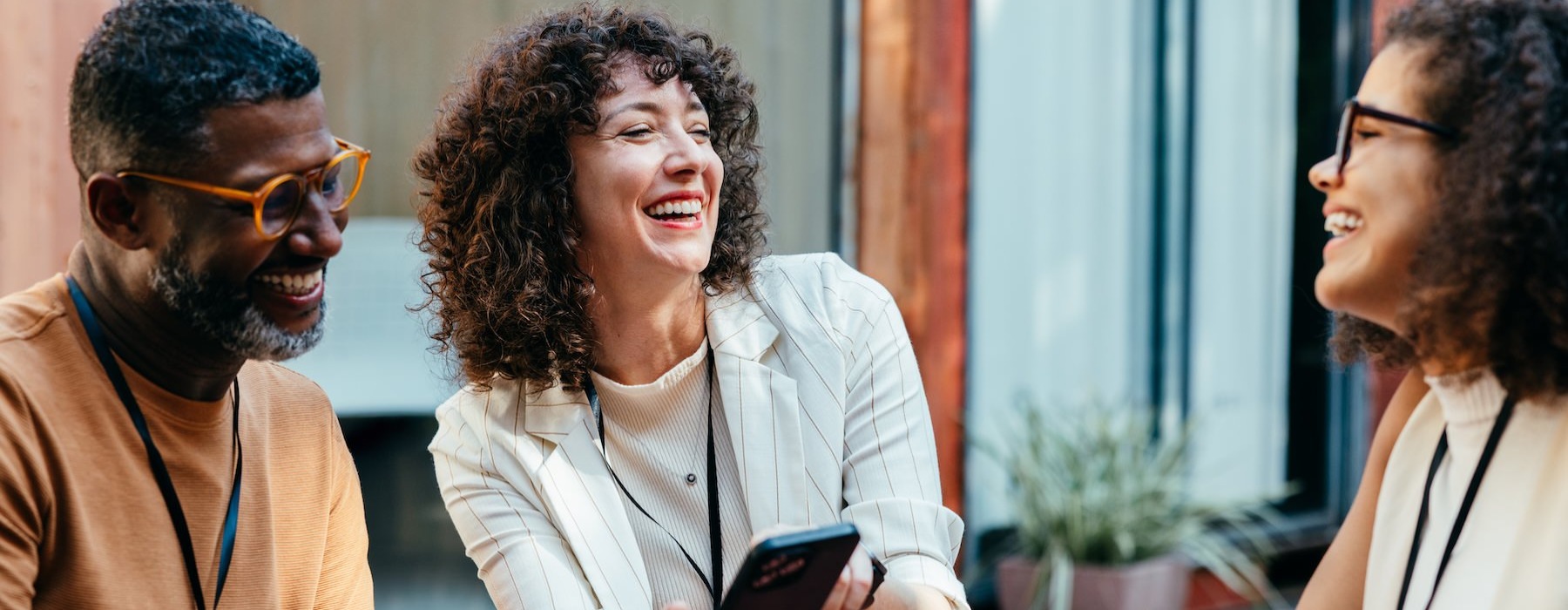 three people laughing and holding a phone